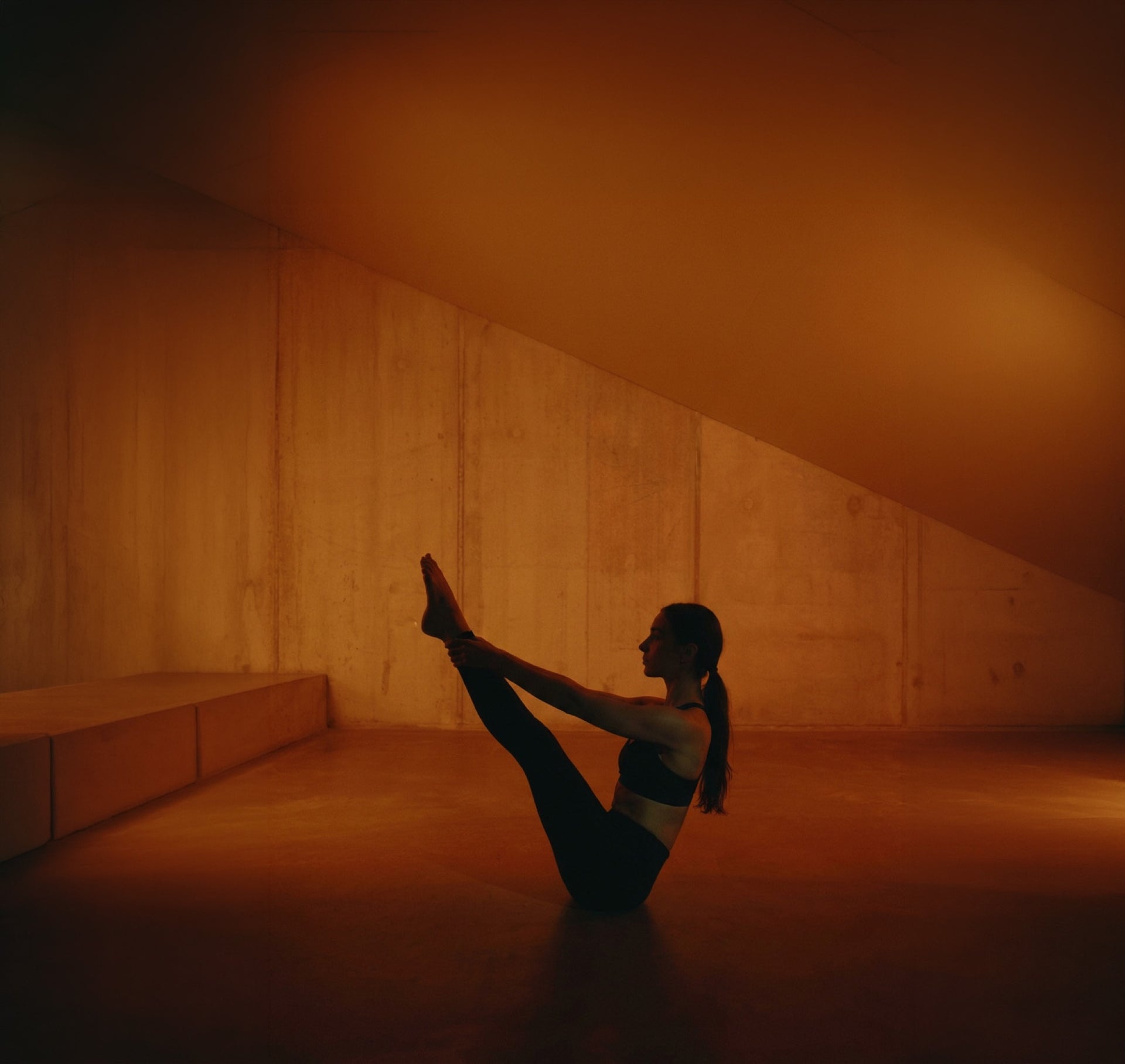 Woman in boat pose in a warm-lit studio